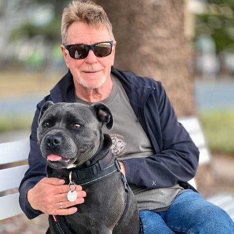 House sitter Lawrie holding Toby the Staffordshire terrier while sitting a park bench